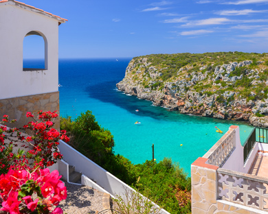 Holiday villa overlooking Cala Porter bay with turquoise sea water, Menorca island, Spain